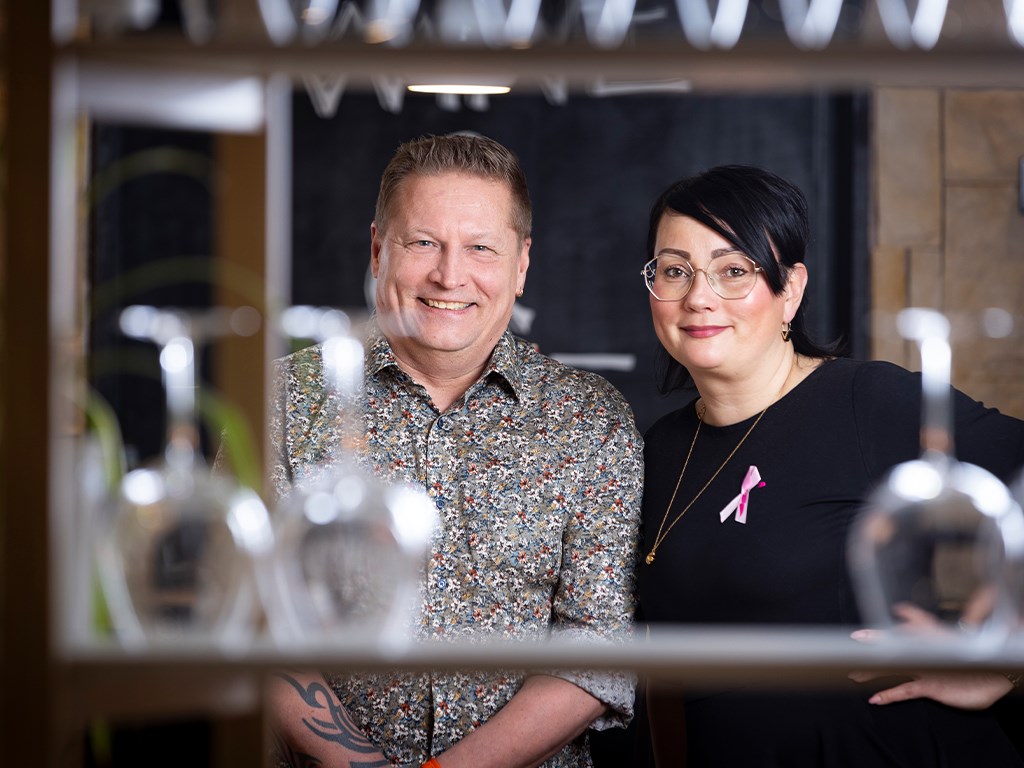 Hymyilevät ihmiset viinilasien takana