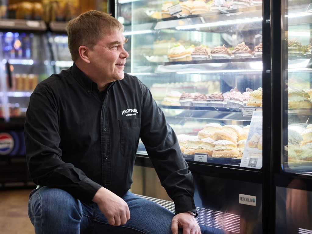 Mies kyykyssä kakkuvitriinin vieressä